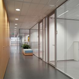 Corridor with on the right side iQ Structural glass system wall with seamless panel joins.