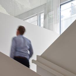 Man at staircase with glass at Leiden University College The Hague