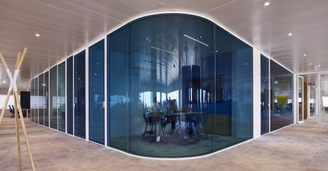 Blue curved glasss for round corners in a double glass partition wall